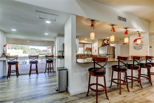 kitchen featuring freestanding refrigerator, light wood-style flooring, dark countertops, white cabinetry, and recessed lighting