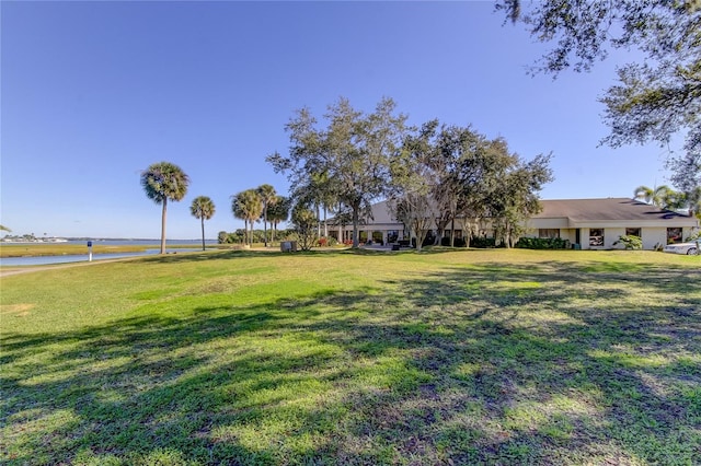view of green lawn featuring a water view