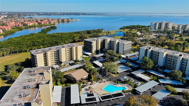 drone / aerial view of a large body of water, apartment complex / building, and a pool area