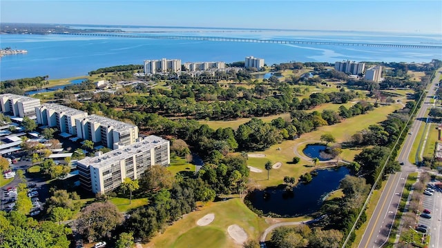 drone / aerial view of a large body of water, apartment complex, a golf course, and a tree filled landscape