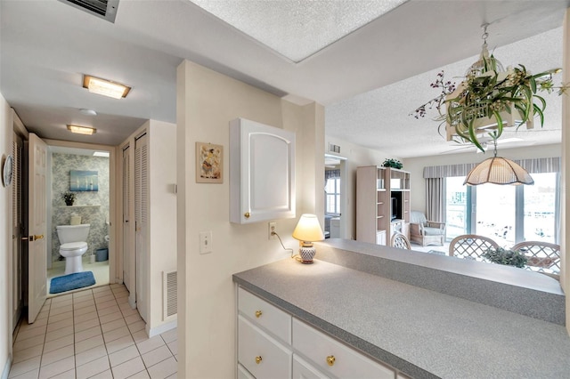 4900 Brittany Dr S Unit 805, Saint Petersburg, FL 33715 - kitchen featuring light tile patterned flooring, white cabinetry, and a textured ceiling