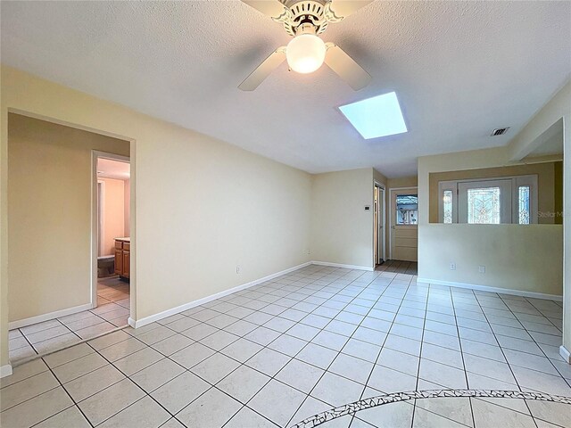 232 Pinecrest Dr, Palm Harbor, FL 34683 - spare room featuring light tile patterned floors, a ceiling fan, a skylight, and a textured ceiling