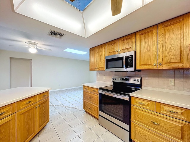 232 Pinecrest Dr, Palm Harbor, FL 34683 - kitchen featuring stainless steel appliances, backsplash, brown cabinets, and a ceiling fan
