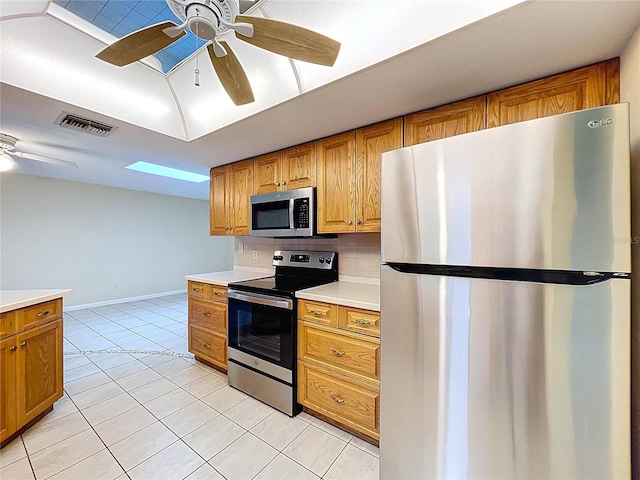 232 Pinecrest Dr, Palm Harbor, FL 34683 - kitchen with stainless steel appliances, ceiling fan, light countertops, light tile patterned floors, and brown cabinetry