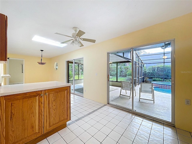 232 Pinecrest Dr, Palm Harbor, FL 34683 - kitchen with a sunroom, ceiling fan, light countertops, brown cabinets, and hanging light fixtures