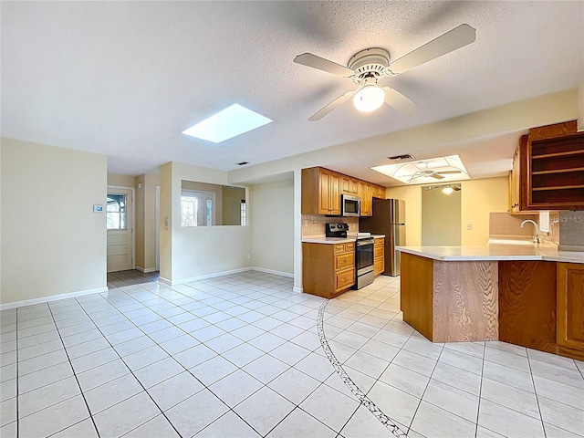 232 Pinecrest Dr, Palm Harbor, FL 34683 - kitchen featuring stainless steel appliances, a skylight, light countertops, ceiling fan, and open shelves