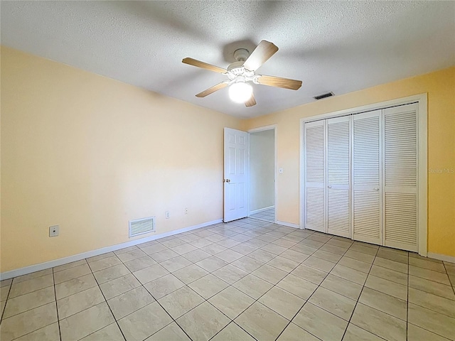 232 Pinecrest Dr, Palm Harbor, FL 34683 - unfurnished bedroom with light tile patterned floors, a closet, a textured ceiling, and a ceiling fan