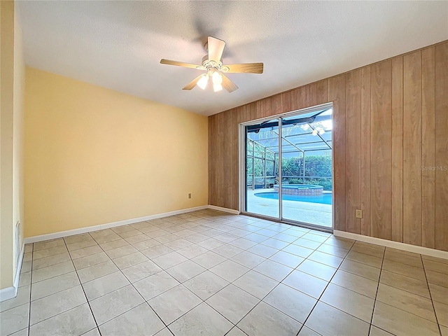 232 Pinecrest Dr, Palm Harbor, FL 34683 - unfurnished room with a ceiling fan, light tile patterned flooring, wooden walls, and a sunroom