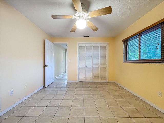 232 Pinecrest Dr, Palm Harbor, FL 34683 - unfurnished bedroom featuring light tile patterned flooring, a closet, ceiling fan, and a textured ceiling