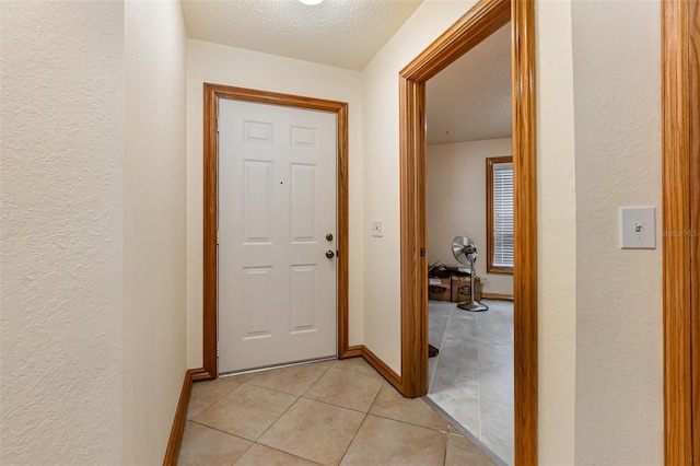 entryway featuring a textured ceiling, a textured wall, and light tile patterned flooring
