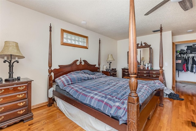 bedroom with a textured ceiling, visible vents, light wood-style flooring, and a ceiling fan