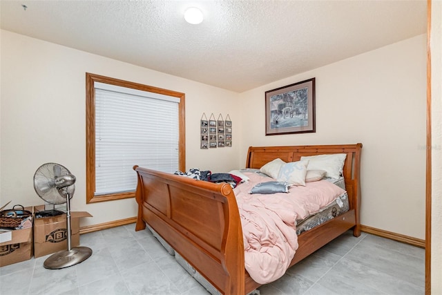 bedroom with baseboards, light tile patterned floors, and a textured ceiling