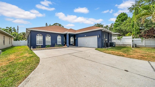 ranch-style home featuring an attached garage, driveway, stucco siding, and central AC unit
