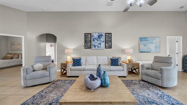 living room featuring light tile patterned floors, a ceiling fan, and arched walkways