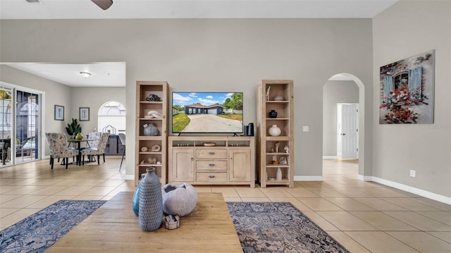 living room featuring arched walkways, light tile patterned flooring, and baseboards