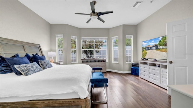 bedroom with dark wood finished floors, multiple windows, baseboards, and ceiling fan