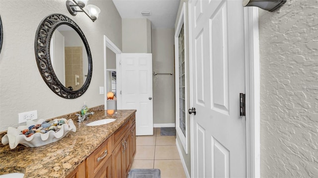 bathroom featuring tile patterned floors, vanity, and a textured wall