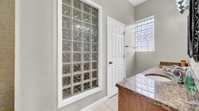 full bathroom featuring tile patterned floors, vanity, a walk in shower, and a textured wall