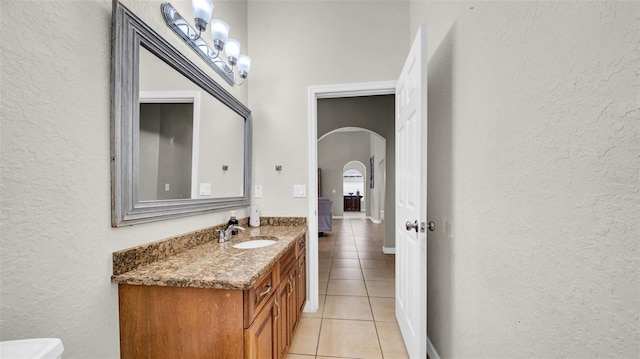 bathroom with a textured wall, tile patterned floors, and vanity