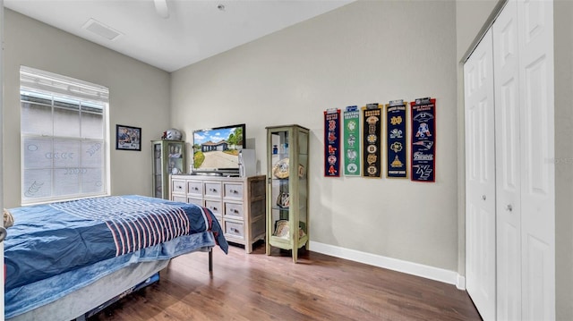 bedroom featuring baseboards, dark wood-style flooring, a closet, and ceiling fan