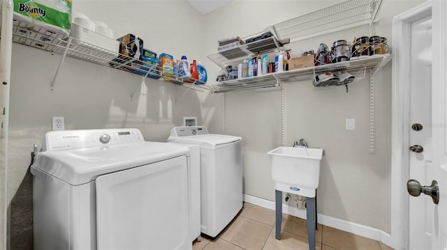 laundry area featuring washer and dryer, light tile patterned floors, and baseboards
