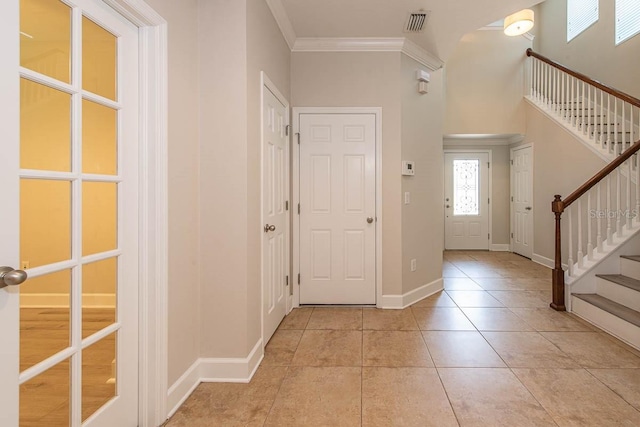 foyer with stairway, crown molding, light tile patterned flooring, and baseboards