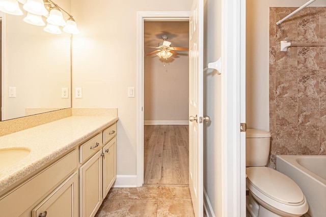 bathroom with vanity, toilet, ceiling fan, baseboards, and tub / shower combination