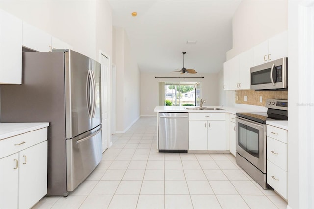 kitchen with a sink, a peninsula, stainless steel appliances, white cabinetry, and decorative backsplash