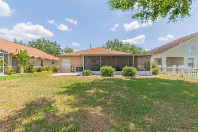 back of house with a yard, a sunroom, stucco siding, and fence