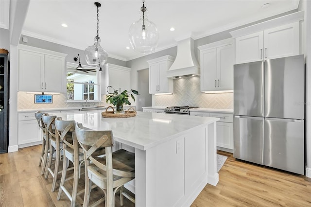 14902 Sweat Loop Rd, Wimauma, FL 33598 - kitchen with appliances with stainless steel finishes, premium range hood, a center island, white cabinets, and crown molding