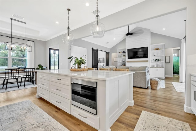 14902 Sweat Loop Rd, Wimauma, FL 33598 - kitchen featuring a barn door, light countertops, white cabinets, light wood finished floors, and pendant lighting