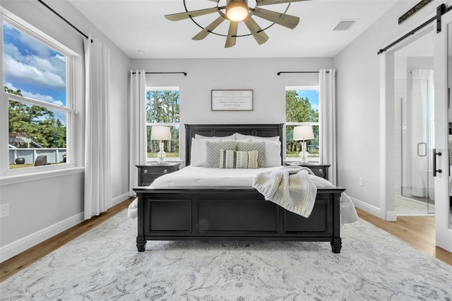 14902 Sweat Loop Rd, Wimauma, FL 33598 - bedroom featuring a barn door, multiple windows, light wood-style floors, and baseboards