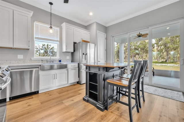 14902 Sweat Loop Rd, Wimauma, FL 33598 - kitchen with a sink, appliances with stainless steel finishes, white cabinets, plenty of natural light, and ornamental molding