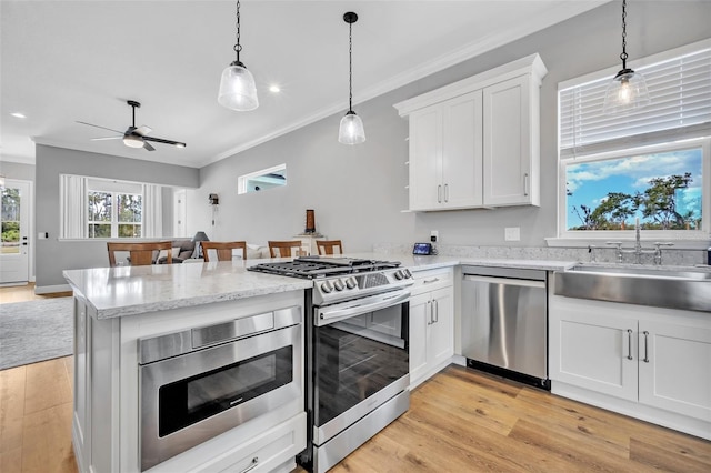 14902 Sweat Loop Rd, Wimauma, FL 33598 - kitchen featuring appliances with stainless steel finishes, a sink, a peninsula, crown molding, and light wood-type flooring