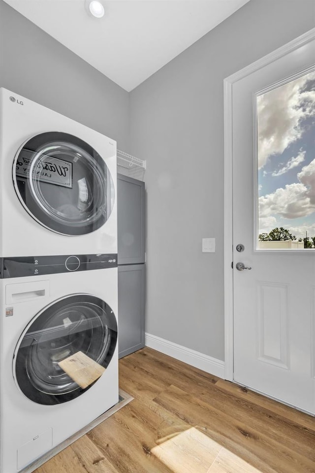 14902 Sweat Loop Rd, Wimauma, FL 33598 - laundry room featuring stacked washer / drying machine, light wood finished floors, and baseboards