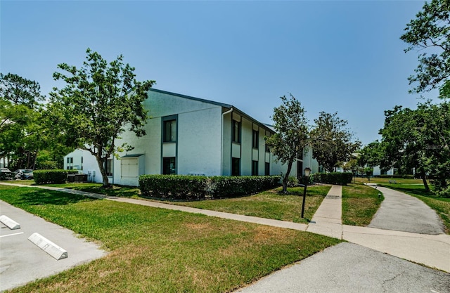 1290 Pine Ridge Cir E Unit G1, Tarpon Springs, FL 34688 - view of property exterior featuring a lawn and stucco siding