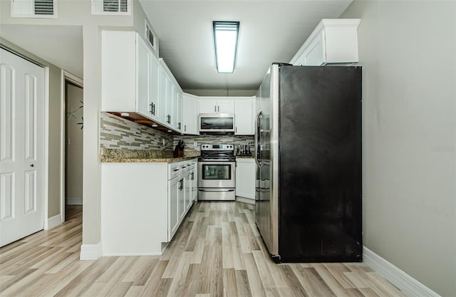 1290 Pine Ridge Cir E Unit G1, Tarpon Springs, FL 34688 - kitchen featuring stainless steel appliances, light wood finished floors, white cabinetry, tasteful backsplash, and baseboards