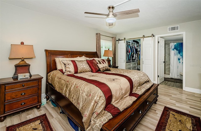 1290 Pine Ridge Cir E Unit G1, Tarpon Springs, FL 34688 - bedroom featuring light wood-style flooring, a barn door, a spacious closet, a closet, and ceiling fan