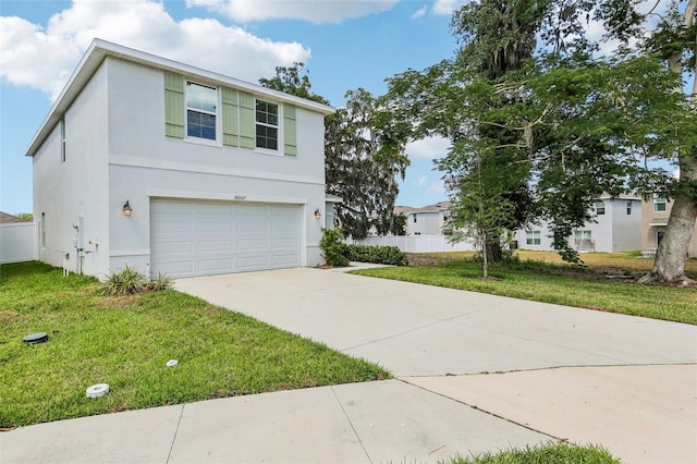 view of front of house featuring an attached garage, driveway, fence, and a front lawn