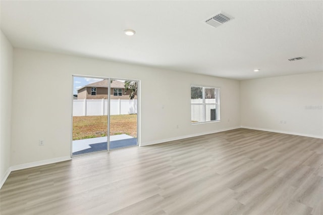 spare room with light wood-style flooring, plenty of natural light, and visible vents
