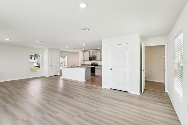 unfurnished living room featuring light wood-style floors, baseboards, and recessed lighting
