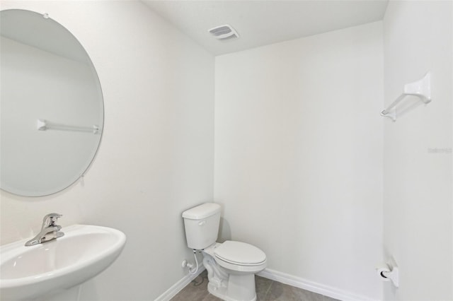 half bathroom featuring a sink, toilet, baseboards, and visible vents