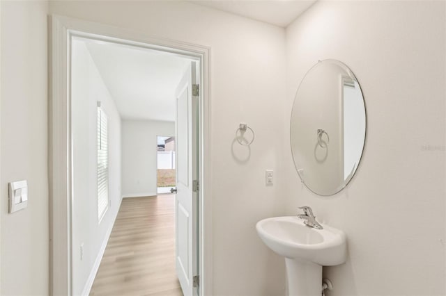 bathroom with wood finished floors, baseboards, and a sink