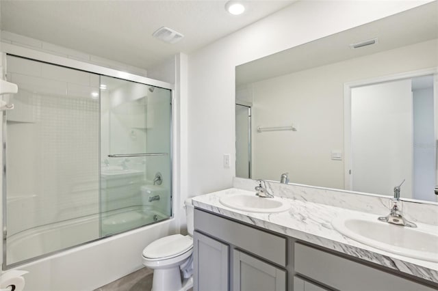 bathroom with a sink, shower / bath combination with glass door, and visible vents