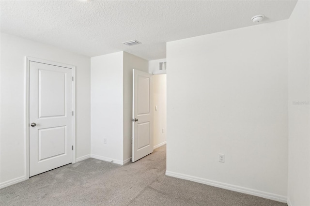 unfurnished bedroom featuring carpet, a textured ceiling, visible vents, and baseboards