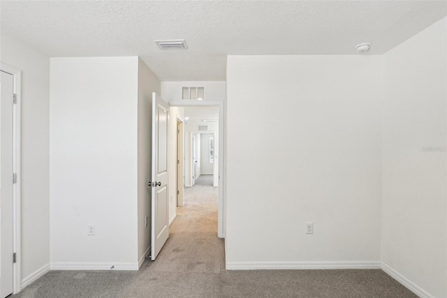 spare room featuring light colored carpet, baseboards, and visible vents