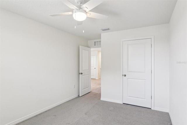 unfurnished bedroom featuring light carpet, baseboards, visible vents, and ceiling fan