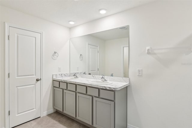 full bathroom with a sink, double vanity, baseboards, and tile patterned floors