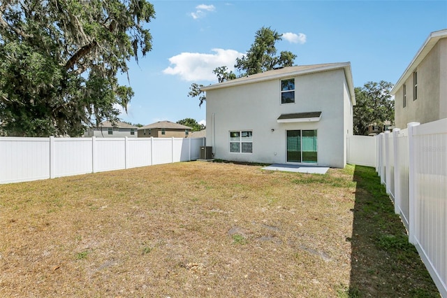 back of property featuring a yard, a fenced backyard, stucco siding, and central AC