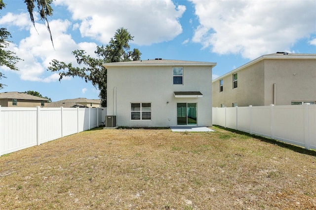back of house with cooling unit, stucco siding, a fenced backyard, and a yard